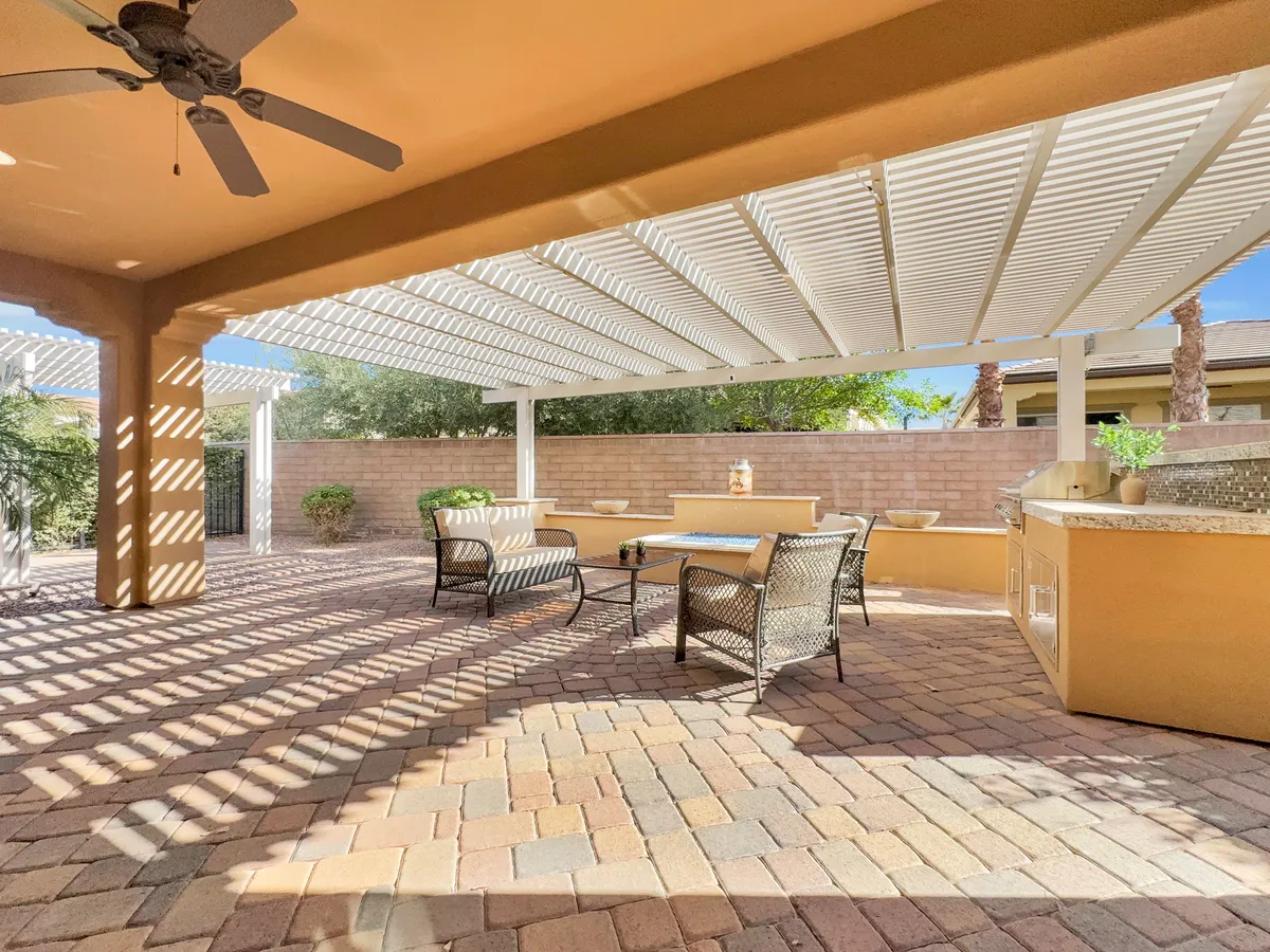 A welcoming outdoor seating area beneath a pergola, complete with an outdoor kitchen and shaded space for social gatherings. The setup is ideal for family barbecues, sunset dinners, or casual relaxation in a comfortable and stylish environment.