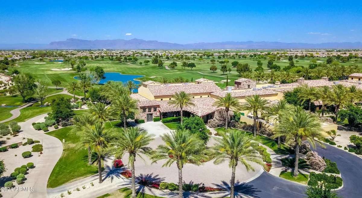 A picturesque exterior shot featuring a luxurious home overlooking a manicured golf course, bordered by lush greenery and a serene water body. The composition invites viewers to imagine relaxing mornings or social gatherings in an idyllic, active community setting.
